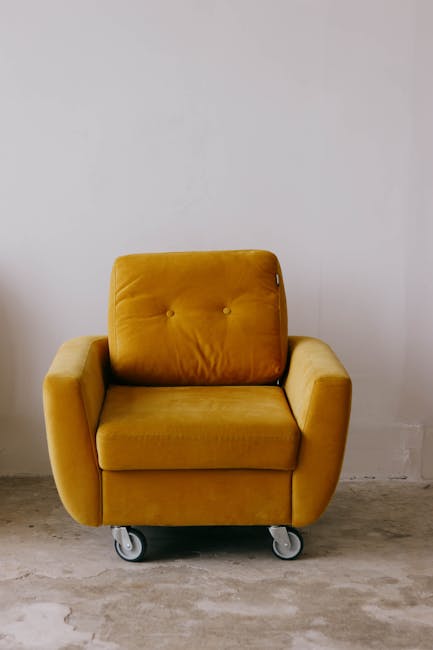 A pristine, white upholstered sofa with tufted cushioning and rolled armrests positioned against a decorative white wall panel with molding, set on a wooden floor. The sofa appears clean and well-main